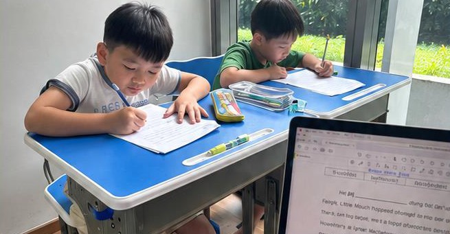 Two Primary 2 boys writing at their desks